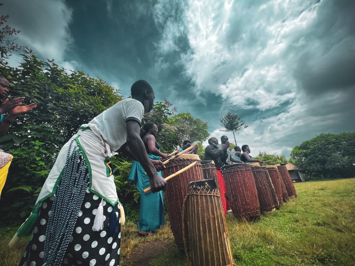 A group of people performing a traditional drumming ritual outdoors under a moody sky.