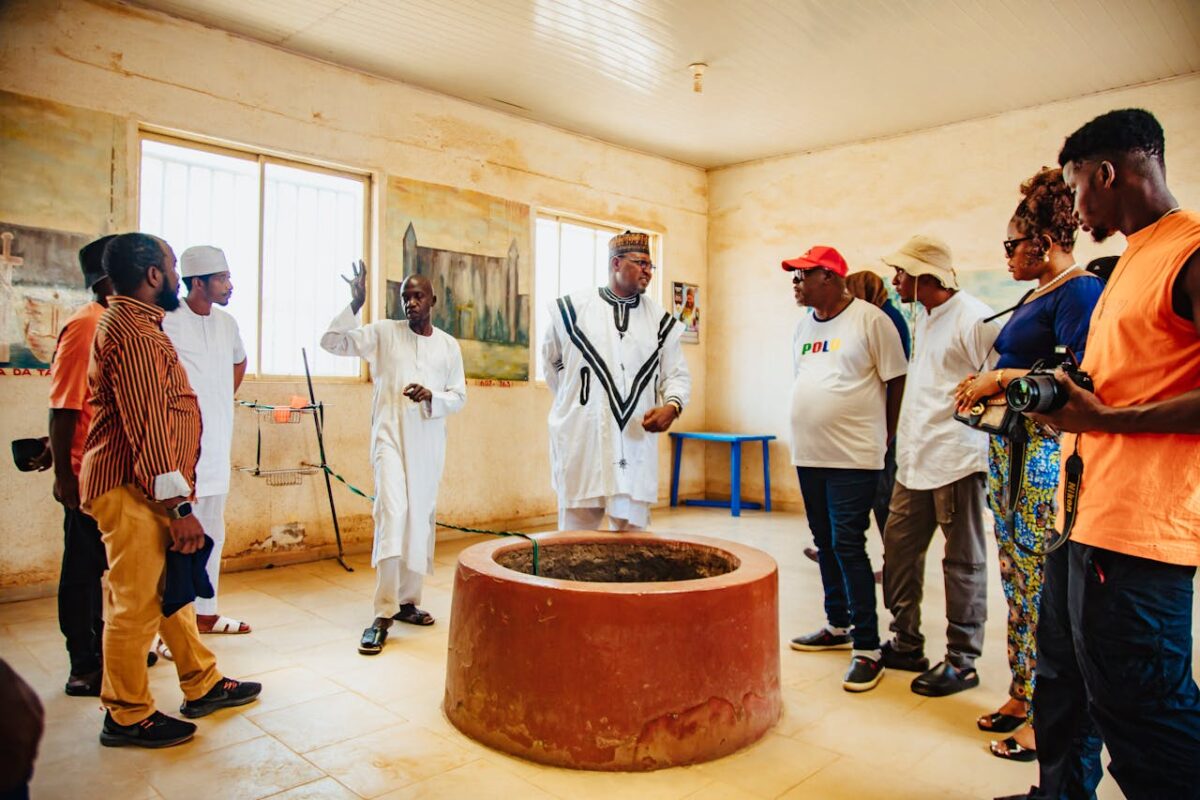 A diverse group of adults touring a historical site indoors with a guide.