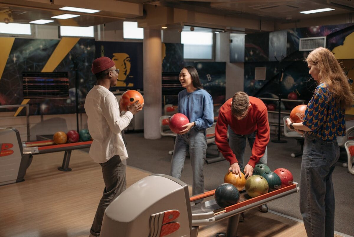 Four friends having a good time while bowling at an indoor bowling alley.