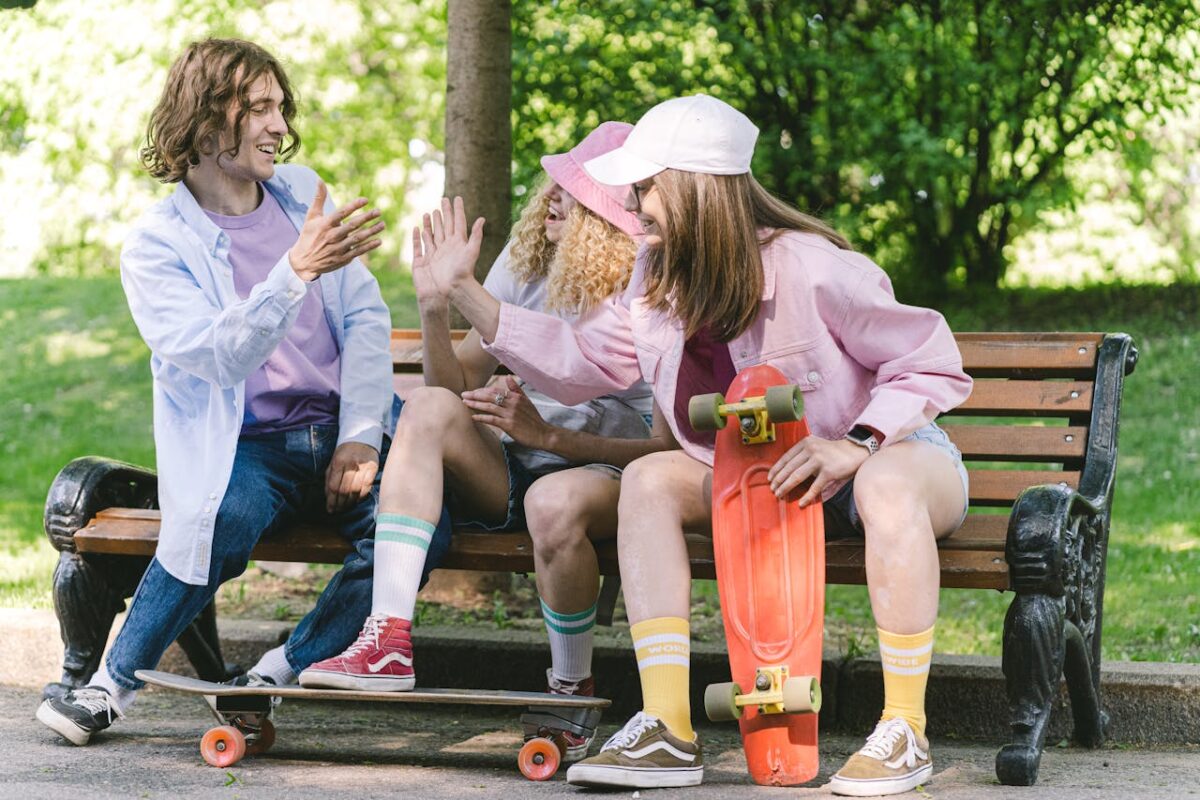 Group of friends enjoying a sunny day in the park with skateboards, high-fiving and smiling.